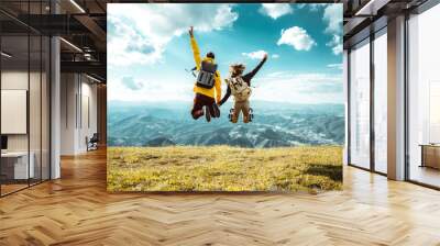 Hikers with backpacks jumping with arms up on top of a mountain - Couple of young happy travelers climbing the peak - Family, travel and adventure concept Wall mural