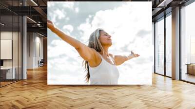 Joyful senior woman enjoying freedom standing with open arms and a happy smile looking up towards the sky - People and happiness concept	
 Wall mural