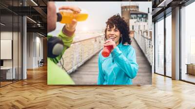 Man and woman drinking energy drink from bottle after fitness sport exercise Wall mural