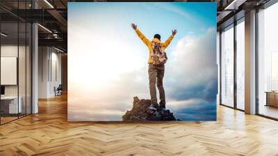 Man traveler on mountain summit enjoying nature view with hands raised over clouds - Sport, travel business and success, leadership and achievement concept Wall mural