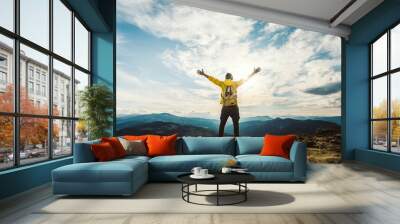 Man traveler on mountain summit enjoying nature view with hands raised over clouds - Sport, travel business and success, leadership and achievement concept Wall mural