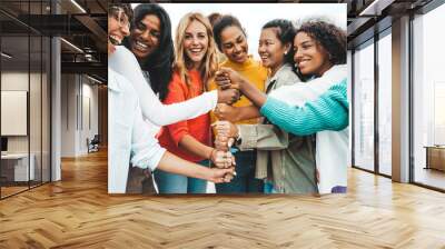 Multicultural group of women stacking hands together - Female community concept with different girls support each other - Girlfriends hugging outdoors Wall mural