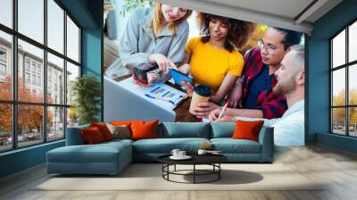 Multiracial diverse coworkers using tablet device on creative office - College students with laptop while sitting at table - Group study for school assignment Wall mural