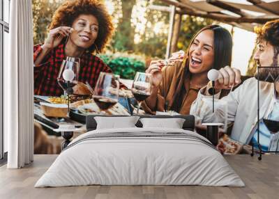 Multiracial friends having fun at barbecue dinner party in garden restaurant - Millennial people cheering red wine sitting at outside bar table - Youth lifestyle, food and beverage concept Wall mural