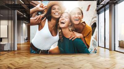 Three multiracial young women having fun walking on city street - Happy girlfriends hanging outside on a sunny day - Different females laughing together outside - Life style and friendship concept Wall mural