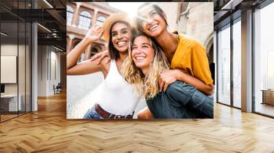 Three young diverse women having fun on city street outdoors - Multicultural female friends enjoying a holiday day out together - Happy lifestyle, youth and young females concept Wall mural