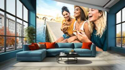 Three young female friends sitting outdoor and eating pizza - Happy women having fun enjoying a day out on city street - Happy lifestyle concept Wall mural