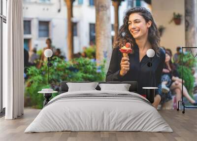 Smiling tourist girl walking with ice cream for a city, holiday Wall mural