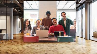 Smiling multiethnic coworkers looking at camera making team picture in modern office together - Happy diverse work group or department laugh posing for photo at workplace - Show unity and cooperation Wall mural