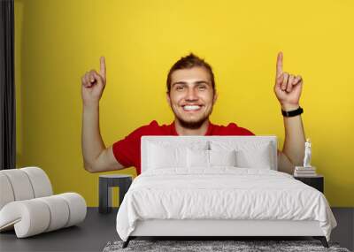 Image of emotional young happy man posing isolated over yellow background pointing Wall mural