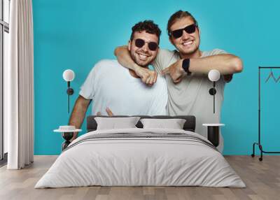 Two young hipster men have good relationship and truthful friendship, embarce each other and smile gladfully, happy to meet after long time. Interracial friendship concept Wall mural