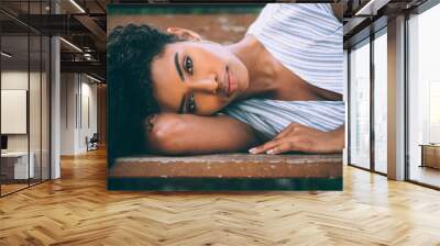 Beautiful young black woman laying down on a chair in a park Wall mural