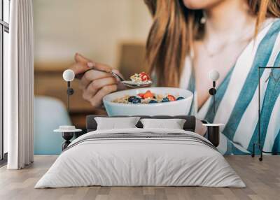 Crop woman close up eating oat and fruits bowl for breakfast Wall mural