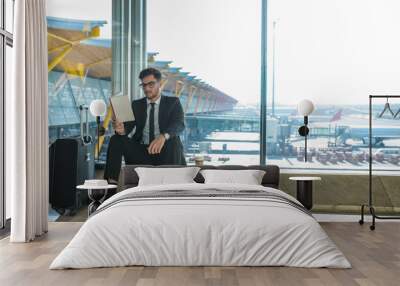 handsome businessman reading a book in the airport sitting close to the window Wall mural