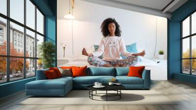 Happy beautiful young black woman relaxed  at home doing morning meditation in bed . Wall mural