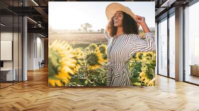 Happy young black woman in a sunflower field Wall mural