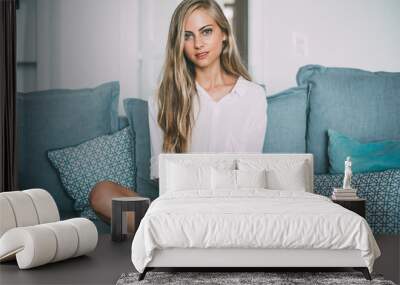 Portrait of a young thoughtful blonde woman sitting in the sofa Wall mural