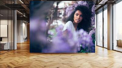 Young black woman sitting surrounded by flowers Wall mural