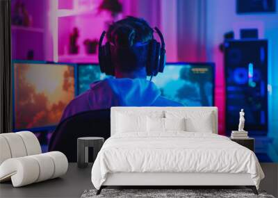 Back view of young man gamer using computer playing game brooding cast online social media with colorful Led light decoration. E-sport technology content creator lifestyle concept. Wall mural