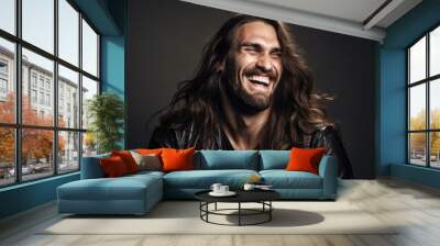 Man smiling with long brown hair standing in front of a black backdrop Wall mural