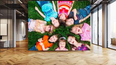 A group of children lying on the green grass in the Park. The interaction of the children. Wall mural