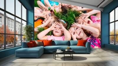 A group of children lying on the green grass in the Park. The interaction of the children. Wall mural