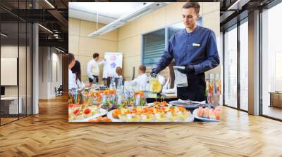 A young waiter pours drinks for catering. Wall mural