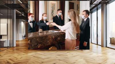 Check in hotel. receptionist at counter in hotel wearing medical masks as precaution against virus. Young woman on a business trip doing check-in at the hotel Wall mural