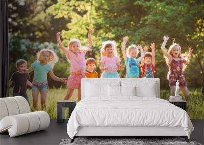 Group of friends running happily together in the grass and jumping. Wall mural