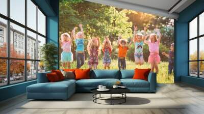 Group of friends running happily together in the grass and jumping. Wall mural