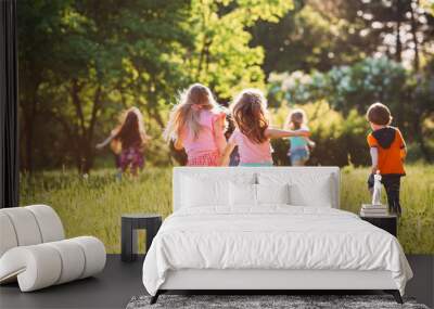 Large group of kids, friends boys and girls running in the park on sunny summer day in casual clothes . Wall mural