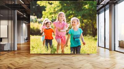 Large group of kids, friends boys and girls running in the park on sunny summer day in casual clothes . Wall mural