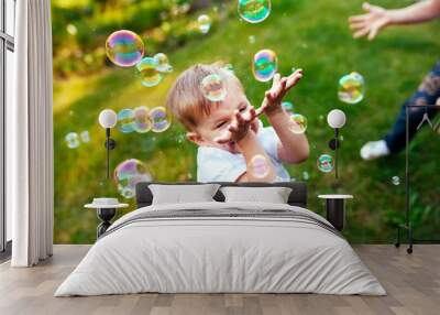 Little boy with soap bubbles in summer park. Wall mural