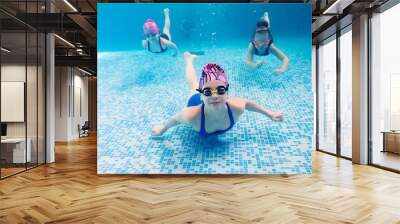 Underwater photo of young friends in swimming pool. Wall mural