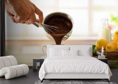 Man filling a cup of fresh hot chocolate from saucepan Wall mural