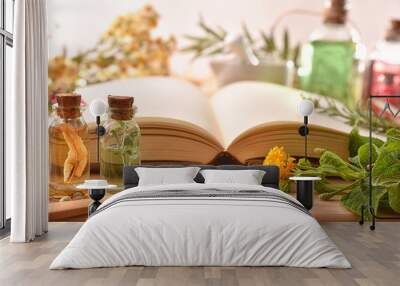 Traditional medicine with herbs and book on table front view Wall mural