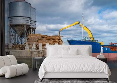 Crane with wood logs gripple loading timber on cargo ship for export in Wicklow commercial port. Transport industry in Ireland Wall mural