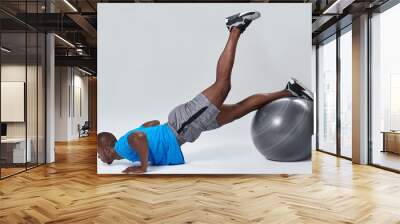 man doing leg lift back exercise routine on gym fitness ball Wall mural