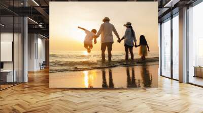 Happy asian family jumping together on the beach in holiday. Silhouette of the family holding hands enjoying the sunset on the  beach.Happy family and vacations concept. Wall mural