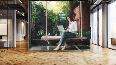 Asian business woman using laptop on swing in garden, Vacation businesswoman working at home, Beautiful hipster girl blogger thinking content with notebook computer, Freelance business people in Asia Wall mural