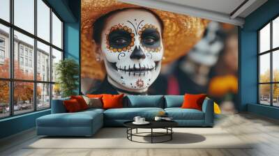 A person with intricate sugar skull makeup and a decorative hat holds a vibrant flower, celebrating Día de los Muertos. Wall mural