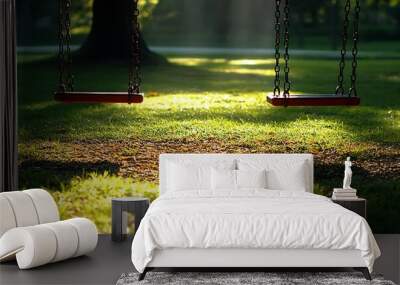 A serene park scene featuring two empty swings on a grassy area illuminated by sunlight. Wall mural