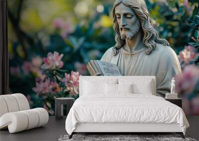 A serene statue of Jesus holding scripture amidst vibrant flowers. Wall mural