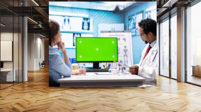 African american medic points at green screen on computer while he consults his patient, exploring treatment plans on health insurance. Physician gives medical advice to ill woman. Wall mural