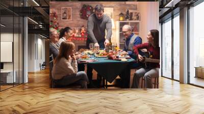 Big family at christmas celebration listening girl singing on guitar. Wall mural