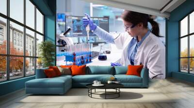 Concentrated professional woman scientist in laboratory working with a micropipette and a dropper. Biology doctor discovery scientifc experiment with technology equipment industry Wall mural