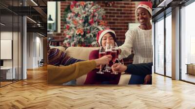 Diverse people clinking alcohol glasses to make toast and celebrate christmas holiday at seasonal office party. Enjoying wine during xmas eve festivity in space with ornaments. Wall mural