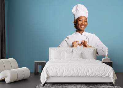 female cook showing heart shaped symbol on camera, expressing romantic gesture and wearing cooking a Wall mural