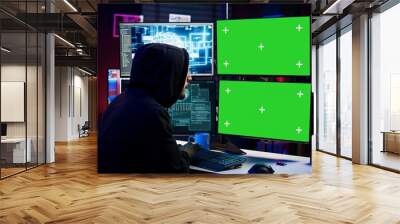 Hacker using AI and green screen computer monitors to produce malicious malware corrupt company data. Evil man working on mockup desktop PC using artificial intelligence, infecting systems, camera B Wall mural