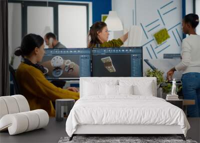 Industrial female engineer looking at personal computer with dual monitors setup, screens showing CAD software with 3D prototype of gears metalic mechanical piece. Employee working in creative office Wall mural